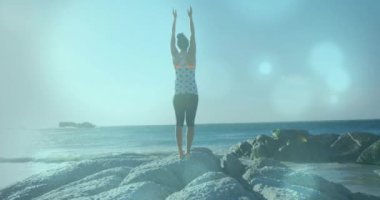 Sahilde yoga yapan melez bir kadının üzerindeki ışık lekelerinin canlandırılması. Spor, doğa ve dijital arayüz konsepti dijital olarak oluşturulmuş video.