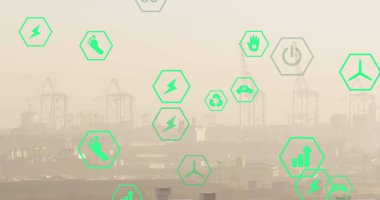 Yeşil dijital simgeler endüstriyel liman sahnesini kaplıyor, vinçler arka planda görünüyor. Enerji yönetimi öneren güç simgeleri ve grafikleri simgeler