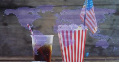 Dünya haritası üzerinde pipetli patlamış mısır ve soda. Atıştırmalık, içecek, sinema, film, eğlence, seyahat