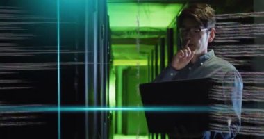 Dizüstü bilgisayarda çalışıyorum, sunucu odasında yeşil ışıkta kodlama animasyonu yapan bir adam var. Teknoloji, programlama, siber güvenlik, veri, altyapı, ağ