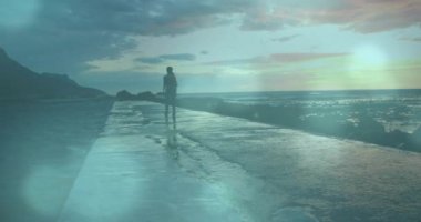 Okyanus kıyısında ıslak yolda yürüyen bir insan, ışık efektleri animasyonuyla. Koşu, fitness, egzersiz, sağlıklı yaşam tarzı, dinamik, hareket