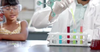 Laboratuvardaki meraklı çocuk yerine moleküler yapıları olan test tüpleriyle ilgilenen bir bilim adamı. Bilim, araştırma, kimya, deney, eğitim, merak