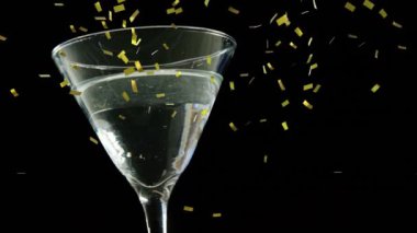 Siyah arka planda martini bardağının üzerinde altın konfeti animasyonu. Kutlama, parti, lüks, cazibe, zarafet, şenlik