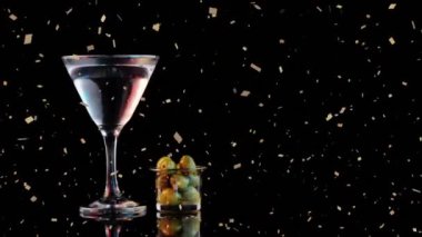 Siyah arka planda altın konfeti animasyonlu martini bardağı ve zeytin. Kokteyl, kutlama, parti, şenlik, cazibe, lüks