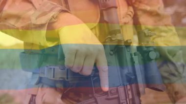 Açık havada tüfeği tutan askerin üzerinde gökkuşağı bayrağı animasyonu. LGBTQ, ordu, gurur, eşitlik, dayanışma, çeşitlilik