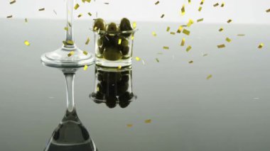 Martini bardağının üzerinde altın konfeti animasyonu ve zeytinli küçük kase. Kutlama, parti, kokteyl, kokteyl, garnitür, şenlik