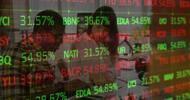 Bu resim, modern bir ofiste birlikte çalışan bir grup grafik tasarımcısını gösteriyor. Çeşitli finansal verilerle borsa görüntüsü.