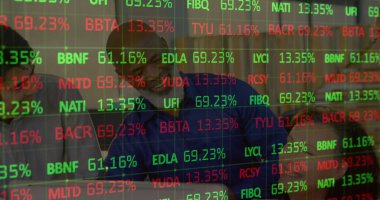 Bir grup işletme yöneticisi, borsa verileriyle çevrili bir şekilde ofiste eğleniyor. Veriler yuvarlanıyor ve işliyor, kırmızı ve yeşil renkler pazarın farklı yönlerini temsil ediyor. 