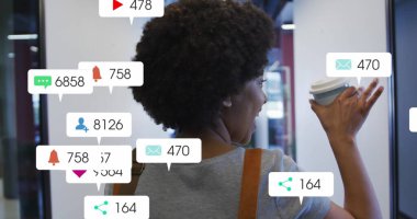 Afro-Amerikalı üniversite öğrencisi telefonu kahveyle kontrol ediyor. Koyu kıvırcık saçları var, omuz çantası ve günlük kıyafetler giyiyor.