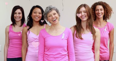 Üzerinde kanser kurdeleleri olan, pembeli, gülümseyen kadınlar grubunun üzerinde yüzen pembe kalplerin resmi. Göğüs kanseri pozitif kadın sağlığı bilinçlendirme kampanyası konsepti dijital olarak oluşturuldu.