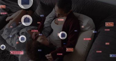 Sosyal medya simgeleri, evde kanepede kızını kucaklayan melez bir annenin görüntüsü. Sosyal medya ağı ve iş teknolojisi kavramı