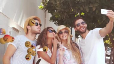 Yüzen emoji animasyonlarıyla çevrili, selfie çeken arkadaşlar. Sosyal medya, eğlence, emojiler, mutluluk, gençlik, açık hava