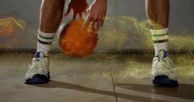 Basketbolcu, bacakları üzerinde altın parçacıklar olan top sürüyor. Spor, atletizm, hareket, eylem, dinamik, enerji