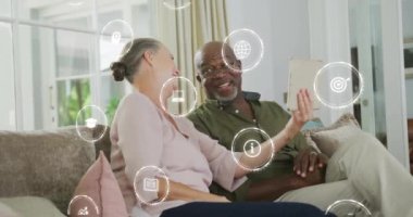 Eğitim ve teknoloji animasyonunu temsil eden simgeler, koltukta tablet kullanan çiftler üzerinde. yenilik, öğrenme, dijital, bağlantı, ev, modern