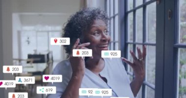 Pencerenin yanında telefonla konuşan bir kadın hakkında sosyal medya bilgilendirmeleri. Teknoloji, iletişim, akıllı telefon, internet, dijital, mesajlaşma
