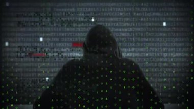 Kapüşonlu bir bilgisayar korsanı ve arka planda veri sızıntısı var. Siber güvenlik, kodlama, teknoloji, tehdit, bilgisayar, şifreleme