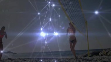 Plaj voleybolu oynayan, ağ bağlantısı olan kadınlar sahilde animasyon yapıyor. Spor, takım çalışması, açık hava