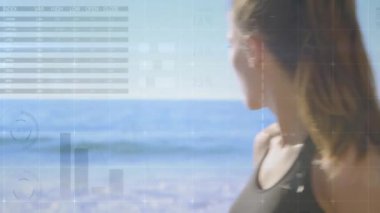 Sahilde duran, grafikleri ve animasyonu olan bir kadın. İş, analitik, veri, dijital, istatistik