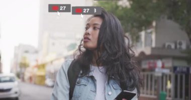 Sosyal medya etkileşimi, şehir ortamında yürüyen bir kadın için animasyon simgeleri oluşturuyor. Teknoloji, dijital, iletişim, bağlantı, yaşam tarzı, siber uzay