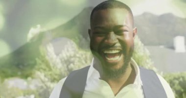 Dışarda gülümseyen bir adam, arka planda dağların ardında bokeh ışığı animasyonuyla. Doğa, erkek, mutluluk, manzara