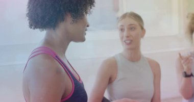 Spor salonunda ışık parçacıkları animasyonuyla konuşan ve gülümseyen kadınlar. Fitness, egzersiz, mutluluk, etkileşim, sağlık, sağlık