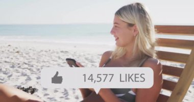 Sahilde oturup akıllı telefon kullanan, animasyonları seven bir kadın. Tatil, sosyal medya, rahatlama, nüfuz, eğlence, teknoloji