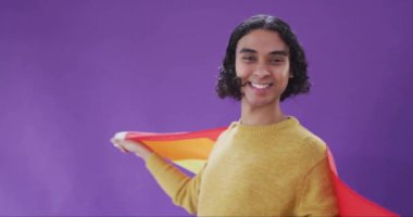 Gökkuşağı bayrağına sarılmış, mor arka planda renkli yumruk animasyonuyla gülümseyen biri. LGBTQ, gurur, çeşitlilik, eşitlik, kutlama, kapsayıcılık