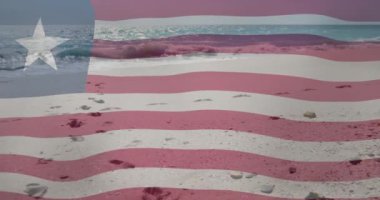 Kumsalda dalgalar ve kumdaki ayak izleriyle Amerikan bayrağını sallıyordu. Vatanseverlik, ABD, okyanus, kutlama