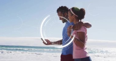 Sahilde akıllı telefonları olan, dijital arayüz animasyonları olan bir çift. Tatil, yaz, teknoloji, artırılmış gerçeklik, aşk, eğlence