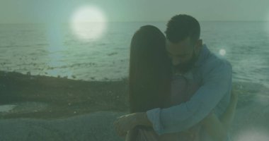 Sahilde birbirini kucaklayan Afrikalı Amerikalı çifte karşı ışık lekeleri. Aşk ve ilişki kavramı