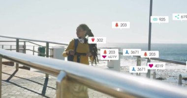 Deniz kenarındaki gezinti alanında yürüyen bir kadın hakkında sosyal medya bilgilendirmeleri. teknoloji, akıllı telefon, dijital, bağlantı, yaşam tarzı, açık hava