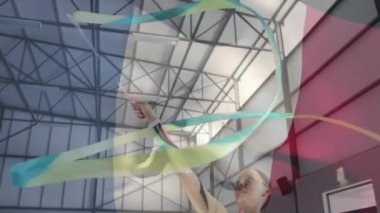 Jimnastikçi iç mekan spor arenasında kurdeleyle renkli girdap hareketleriyle gösteri yapıyor. Jimnastik, performans, aerobik, atletik, rekabet, hareket