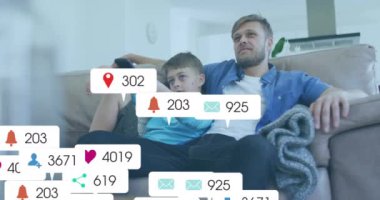 Kanepede televizyon izlemek, sosyal medya bilgilendirmeleriyle çevrili bir adam ve çocuk. Aile, bağ, rahatlama, teknoloji, dijital yaş, babalık