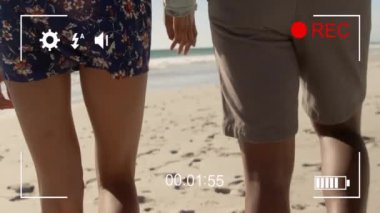 El ele tutuşmalar, plajda yürüyen ve animasyon kaydeden bir çift. Aşk, gün batımı, eğlence, tatil, aşk, okyanus.