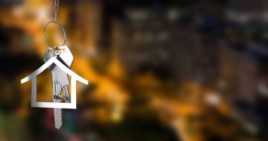 Gümüş renkli ev anahtarlarını fotokopi alanı olan bulanık şehir manzarasına karşı asma görüntüsü. Yerleştirme ve emlak konsepti