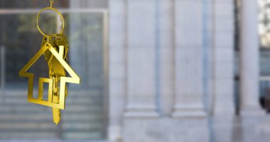 Altın ev anahtarlarını, fotokopi alanı olan binanın bulanık manzarasına asma görüntüsü. Yerleştirme ve emlak konsepti