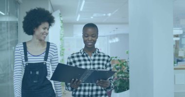 Çeşitli meslektaşlar ve Afrikalı Amerikalı stajyerler yürürken kağıtları tartışırlar. Her ikisi de günlük ofis kıyafetleri giyiyorlar ve keyifli bir anı paylaşıyorlar.