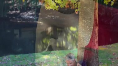 Ağacın altında sonbahar yapraklarıyla oturan çift, Belçika bayrağı animasyonunun üzerinde. Doğa, açık hava, sonbahar, romantizm