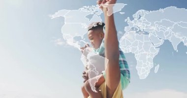 Sahilde yetişkinlerin omuzlarına binen bir çocuğun dünya haritası. Aile, tatil, seyahat, macera, bağ, yaz