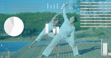 Kafkasyalı çift, doğayla çevrili ahşap güvertede yoga yapıyor. Hafif giysiler giyip, pozisyonlarını korumaya odaklanmışlar.