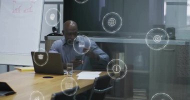 Afro-Amerikan iş adamının ofisindeki dijital simgelerin animasyonu. Küresel finans, iş, bağlantılar, hesaplama ve veri işleme kavramı dijital olarak oluşturulmuş video.