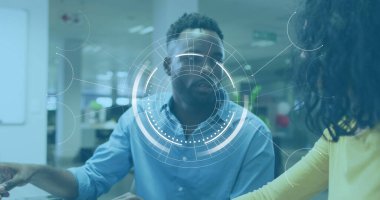 Siyahi erkek analist, çift ırklı kadın yönetici tavsiye ediyor. Her ikisi de gündelik kıyafetler giyiyor, ofiste dijital arayüzle.