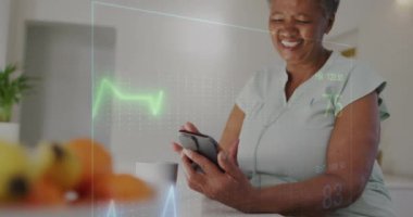Evde akıllı telefon kullanan yaşlı çift ırklı kadının kardiyografisinin animasyonu. Tıp, emeklilik ve dijital arayüz konsepti dijital olarak oluşturulmuş video.
