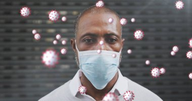 Image of covid 19 cells over african american man wearing face mask. Global covid 19 pandemic concept digitally generated image. clipart