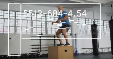 Spor salonunda egzersiz yapan, kutunun üstüne atlayan iki ırklı adamın dijital veri işleme animasyonu. Küresel spor, fitness, bağlantılar, hesaplama ve veri işleme kavramı dijital olarak oluşturulmuş video.