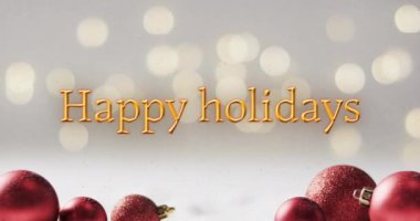 Kırmızı Noel süslemeleri, kar ve bokeh ışıkları olan sarı renkli mutlu bayramlar mesajları. Noel, gelenek, selamlar ve dijital olarak oluşturulan video kutlaması.