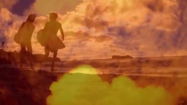 Kumsalda sörf tahtalarıyla koşan beyaz bir çiftin üzerinde mavi gökyüzü ve bulutların animasyonu. Yaşam tarzı, doğa ve dijital arayüz konsepti dijital olarak oluşturulmuş video.