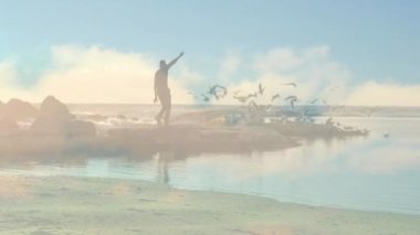 Kumsalda koşan beyaz adamın üzerindeki mavi gökyüzü ve bulutların animasyonu. Yaşam tarzı, doğa ve dijital arayüz konsepti dijital olarak oluşturulmuş video.