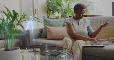 Evde baskı gören yaşlı melez kadının kardiyografisinin animasyonu. Tıp, emeklilik ve dijital arayüz konsepti dijital olarak oluşturulmuş video.