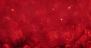 Kırmızı arkaplanda hareket eden parlak ışık noktalarının canlandırması. Renkler, şekiller, ışık ve hareket konsepti dijital olarak oluşturulmuş video.
